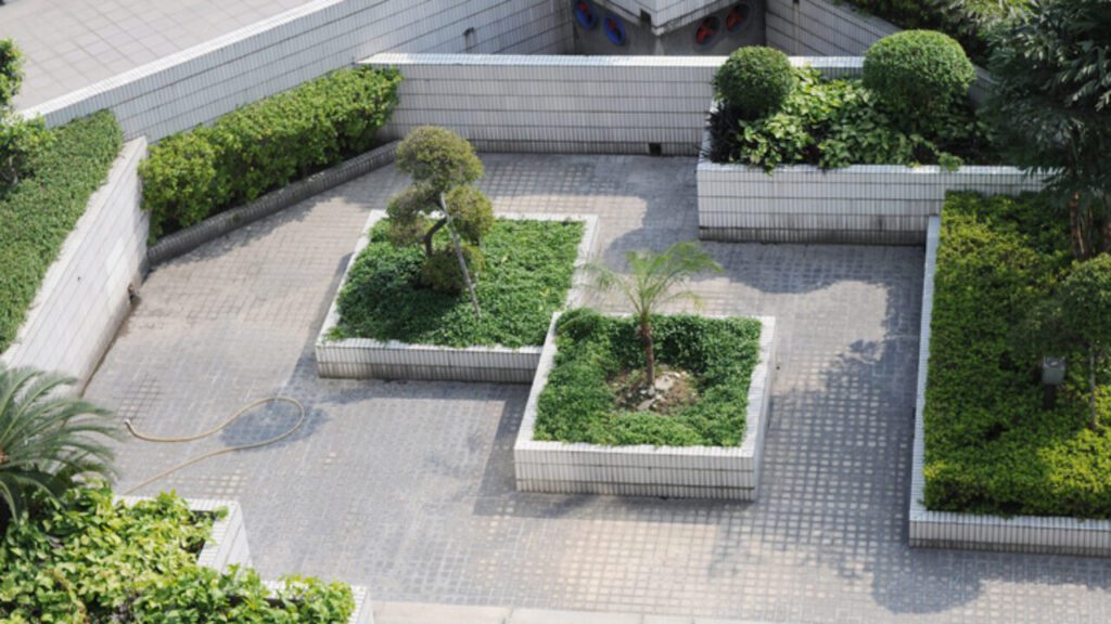A small roof garden with ceramic tile foot path and flower bed.